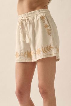 Linen-blend shorts. Floral embroidery. Elastic waist with tassel drawstring. Side pockets. Wide leg. Thigh length. Relaxed fit. 70% Rayon, 30% Linen. Imported. Designed in LA. Model wears size S. Bohemian Short Length Bottoms With Drawstring, Bohemian Embroidered Beige Bottoms, Beige Bohemian Embroidered Bottoms, Cream Floral Embroidery Bottoms For Summer, Summer Floral Embroidery Cream Bottoms, Summer Cream Bottoms With Floral Embroidery, Casual Floral Embroidery Bottoms For Vacation, Casual Floral Embroidered Bottoms For Vacation, Casual Vacation Bottoms With Floral Embroidery