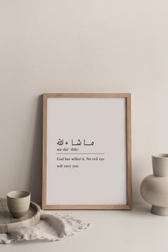 an arabic quote is displayed on a shelf next to a cup and saucer in front of a white wall