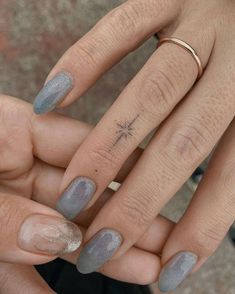 two hands holding each other with grey and white nail polishes on their fingertipss