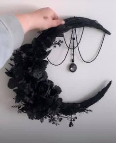 a person holding a black necklace with flowers and chains attached to the back of it