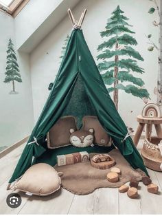 a green teepee tent sitting on top of a floor next to pillows and toys