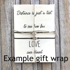 a gift wrapped in white paper with the words distance is just a test to see how far love can travel