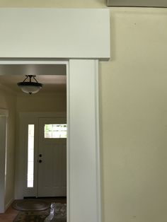 an open door leading to a hallway with a bird on the floor and a light fixture above it