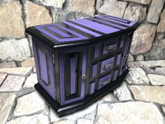 a purple and black cabinet sitting on top of a stone floor