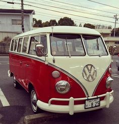 a red and white vw bus parked in a parking lot next to other cars