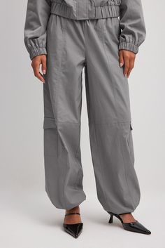 These cargo pants feature an elastic waistband with a drawstring. They have two side pockets and two back pockets. These cargo pants feature side pockets along each leg and a drawstring at the hems. Baggy Gray Cargo Pants With Elastic Waistband, Gray Utility Cargo Pants, Gray Utility Cargo Pants With Multiple Pockets, Gray Tapered Leg Cargo Pants With Pockets, Gray Full-length Cargo Pants With Side Pockets, Gray Full Length Cargo Pants With Side Pockets, Gray Relaxed Fit Cargo Pants With Elastic Waistband, Gray Wide Leg Cargo Pants With Elastic Waistband, Gray Fall Cargo Pants