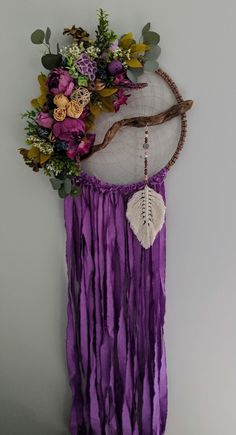 a purple wall hanging with flowers and feathers