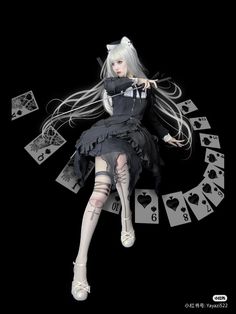 a doll with long hair sitting on top of playing cards