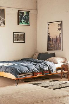 a bed sitting in the middle of a room with pictures on the wall above it