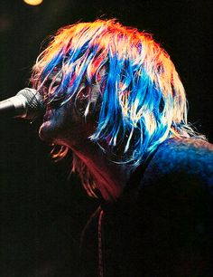 a man with long hair singing into a microphone