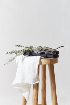 a plant is sitting on top of a wooden stool next to a white shirt and black pants