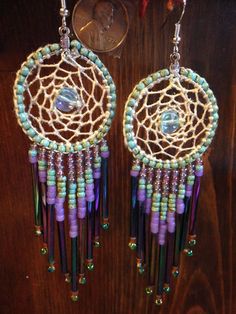 a pair of earrings with beads hanging from it's ear hooks on a wooden table