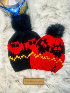 a red and black knitted hat sitting on top of a white fur covered floor