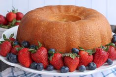 a bundt cake with strawberries and blueberries on the side