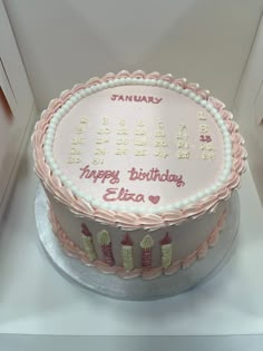 a birthday cake with pink frosting and white icing is displayed in a display case