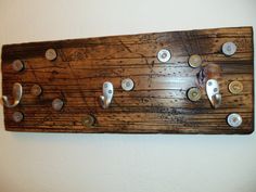 a wooden coat rack with metal knobs and hooks on the top, mounted against a white wall