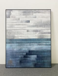 an abstract painting with blue and white colors on the wall in front of a black frame