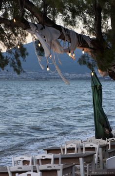 chairs and umbrellas are set up on the beach for an outdoor dining area by the water