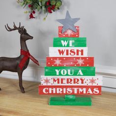 a wooden christmas tree sitting on top of a table next to a toy deer and wreath