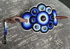 a blue and black brooch sitting on top of a gray couch next to a hook