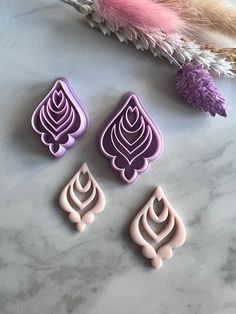 three fondant shapes sitting on top of a marble table next to feathers and flowers