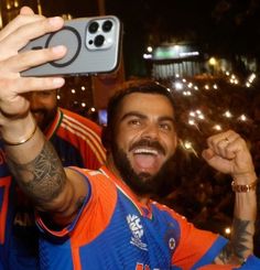 a man taking a selfie with his cell phone in front of an audience at a sporting event