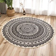 a black and white circular rug on a wooden floor next to a plant in a room