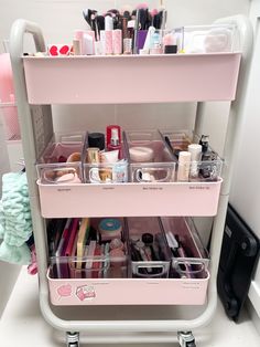 a pink cart filled with lots of cosmetics and other items on top of a white counter