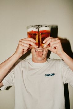 a man holding up two beer glasses to his face