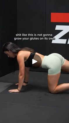 a woman is doing push ups on her stomach and knees while standing in front of a black wall