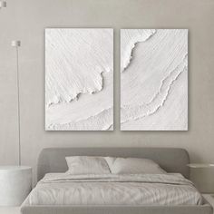 two white paintings on the wall above a bed