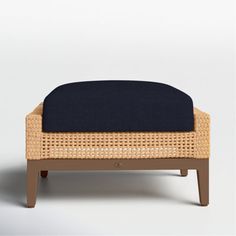 a footstool made out of wicker and blue cushion on top of it