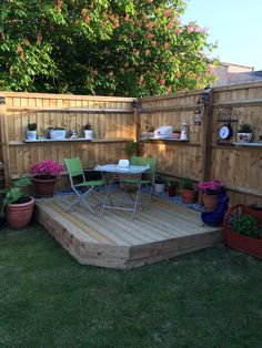 a wooden deck surrounded by potted plants and pots with flowers on it in the back yard