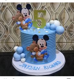 a blue mickey mouse cake with balloons on it and the number five in the middle