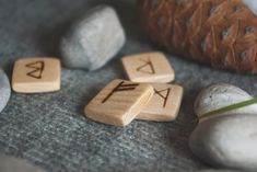 three wooden dices sitting next to some rocks and a pine cone on the ground