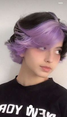 a woman with purple hair wearing a new york t - shirt in front of a white wall