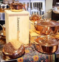 copper pots and pans are on display in a store's kitchen area, with the box for them