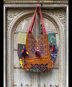 a colorful bag hanging on the side of a wooden door with ornate carvings around it