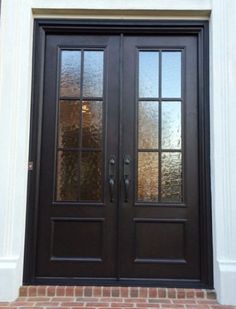 the front door to a house with two double doors and brick walkway leading up to it