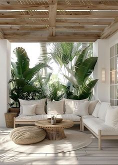 a living room filled with lots of white furniture and large palm trees in the background