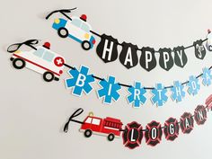 a happy birthday banner with cars and firetrucks hanging from it's side