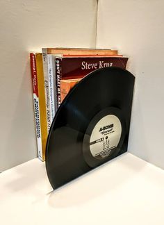 a record sitting on top of a book shelf next to some other books in front of a white wall