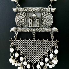 German silver Indian pendant necklace with Taj Mahal in 3D, and a beautiful geometric pendant with faux pearl dangling ghungroo. In a soft grey color with the patina of a vintage piece. Realistic faux pearls Excellent quality and craftsmanship. Necklace measures 12 inch drop. Pendant measures 4.5 inches by 3 inches. View more necklaces here: https://www.etsy.com/shop/BoutiqueByMaryam?section_id=21694658 Be sure to visit the rest of my shop here: https://www.etsy.com/shop/boutiquebymaryam Traditional White Metal Necklace, Traditional White Oxidized Finish Necklace, Traditional White Necklace With Oxidized Finish, Traditional White Necklaces With Oxidized Finish, Bohemian Long Necklace With Pearl Pendant, Traditional Silver Dangle Necklaces, Traditional Silver Jewelry With Pearl Pendant, Bohemian White Jewelry With Latkans, White Bohemian Jewelry With Latkans