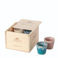 two cups in a wooden box next to each other on a white surface with the lid open