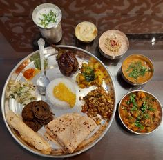 a silver plate topped with lots of different types of food next to bowls and spoons