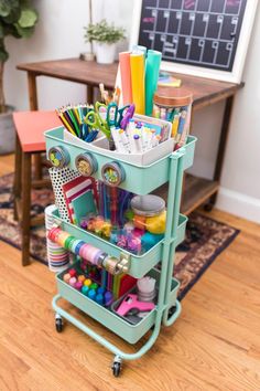 a cart filled with lots of office supplies on top of a hard wood floor next to a table