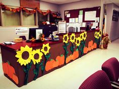 an office decorated for fall with sunflowers and pumpkins painted on the desk