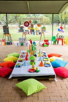 an outdoor birthday party with colorful pillows and decorations on the table, along with other items