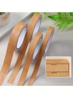 three rolls of wood tape sitting next to each other on a white table with green leaves