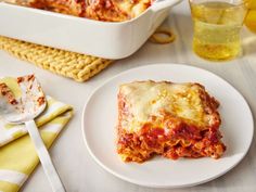 a white plate topped with lasagna next to a casserole dish